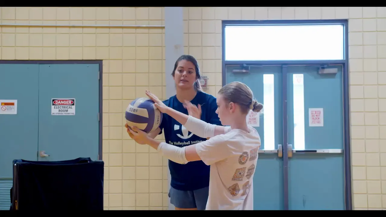 Paulina Prieto Cerame, a TVI Trainer, guiding a young athlete's hands as she holds the ball in her passing platform