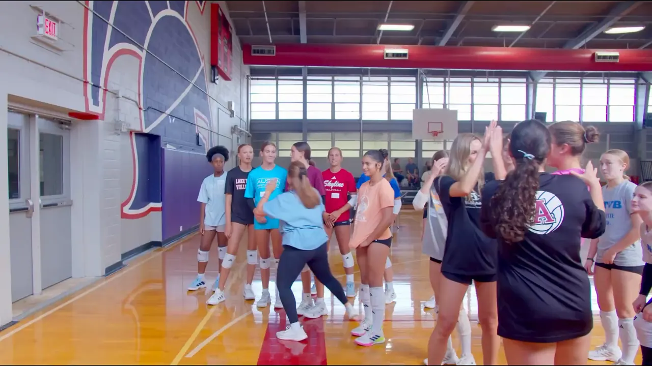 Caitlyn Donahue, a TVI Trainer, high-fiving a line of athletes at a TVI clinic