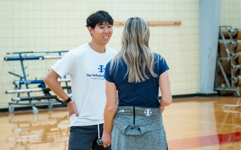 Two TVI Trainers in TVI shirts smiling and talking on court between sessions