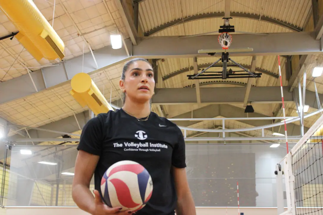 Juliann Faucette, a TVI Trainer, holding a volleyball and looking out across the gym